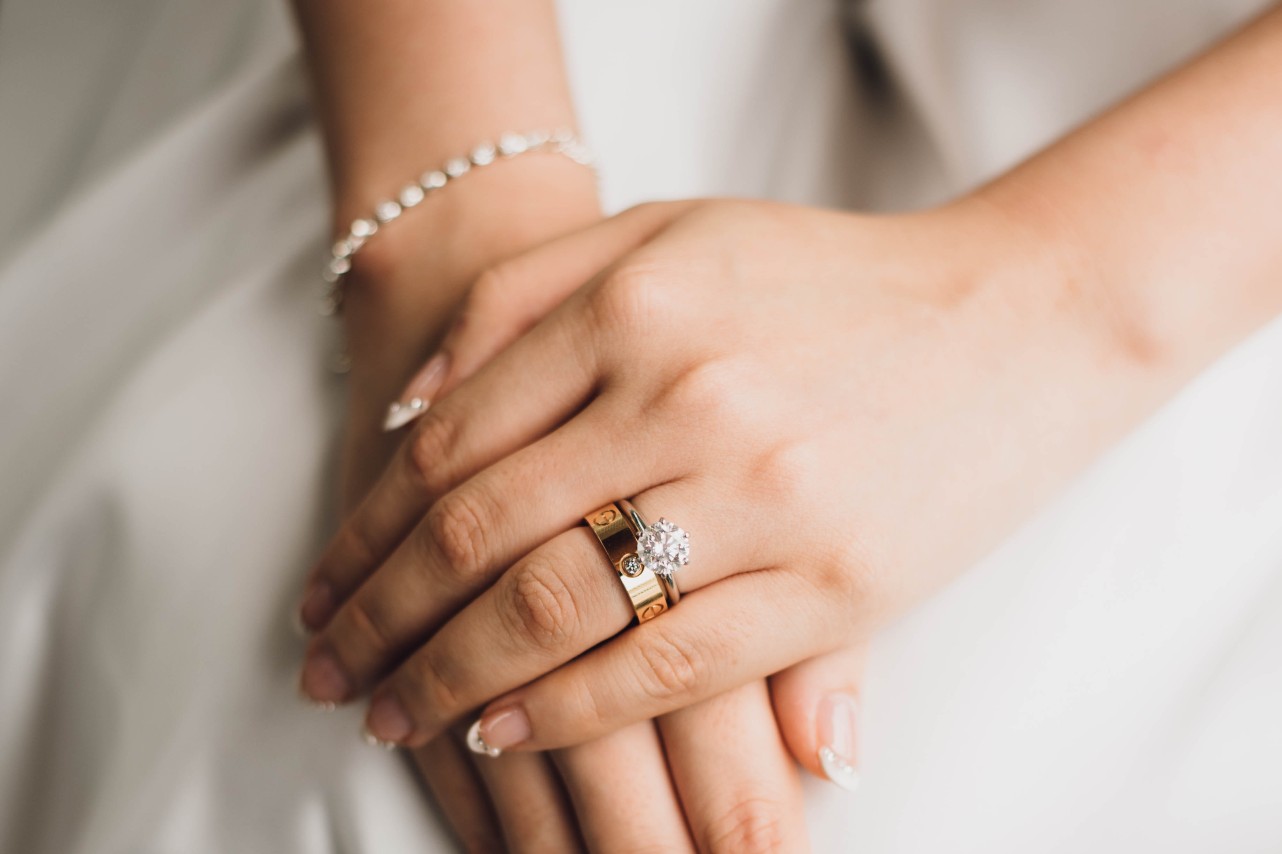 A close-up of a bride’s hands folded over her lap, an elegant bridal stack on her finger.